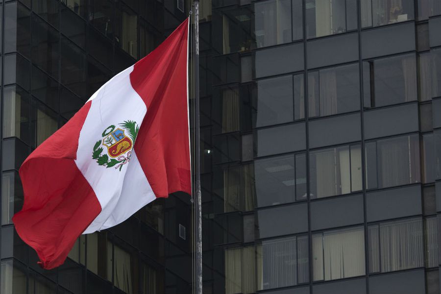 bandera de peru moviendose con el viente frente a un edificio